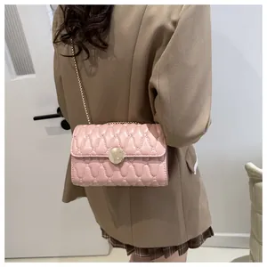 Detailaufnahme der hellrosa gesteppten Umhängetasche mit goldener Kette an einem Model