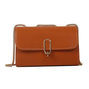 Caramel orange crossbody bag with gold chain strap and contrast stitching on white background