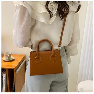 Brown PU leather crossbody bag shown on a model in a cozy, minimalist lifestyle scene