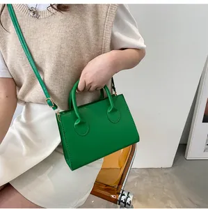 Detail of vibrant green leather handbag with dual cylindrical handles and adjustable strap