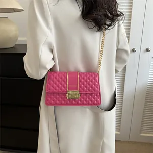 Quilted bright pink crossbody bag with gold chain strap worn over a white blazer