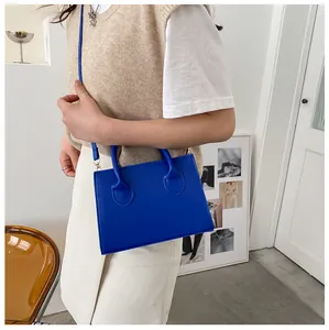 Detail of Klein blue square handbag featuring gold hardware and dual handles