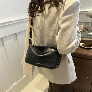 Borsa a tracolla moderna in pelle nera con scritte dorate, indossata da una modella