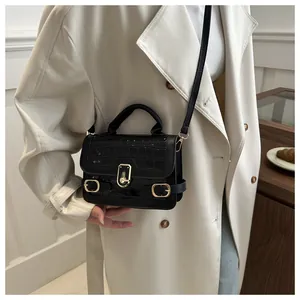 Detail der schwarzen Handtasche mit Steinmuster und Goldverschluss am Model