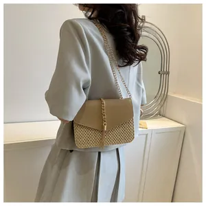 Détail du sac en paille avec rabat en cuir en V et franges à pompons dorés