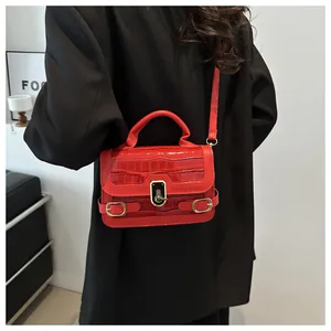 Detail der roten Tasche mit Steinmuster und Goldverschluss auf schwarzem Blazer