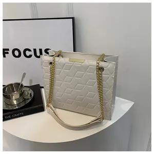 Detail of white embossed tote bag with gold chain strap and modern geometric pattern