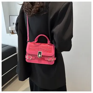 Detail der pinkfarbenen Handtasche mit Krokodilprägung, goldenem Drehverschluss und Akzenten