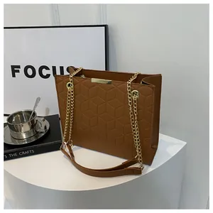 Detail of brown PU leather crossbody bag with geometric embossed pattern and chain strap