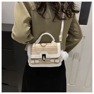 Detailansicht der weiß-beigen Handtasche in Steinoptik getragen zu einem khakifarbenen Blazer
