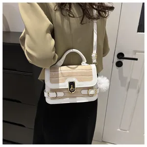 Schicke beige Handtasche mit Krokodilmuster, weißem Rand und goldener Schließe am Model