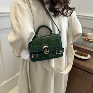 Dunkelgrüne Handtasche mit Steinmuster, goldener Schnalle und Plüschanhänger
