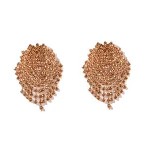 Dettaglio macro di orecchini dorati con frange di strass e design geometrico