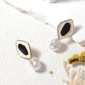 Pendientes de perlas geométricos con esmalte negro y acabado dorado en fondo de piedra