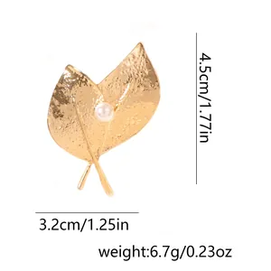 Détail de la broche feuille dorée avec texture martelée et perle blanche centrale