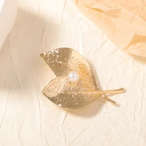 Broche élégante en forme de feuille dorée martelée avec une perle blanche centrale
