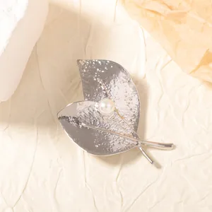 Détail d'une broche feuille argentée avec texture martelée et perle centrale