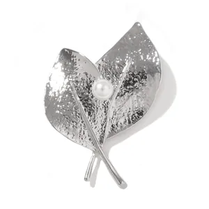 Détail d'une broche feuille argentée avec texture martelée et perle nacrée blanche