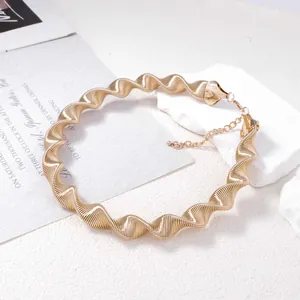 Dettaglio della collana a spirale dorata con strisce verticali e chiusura a moschettone