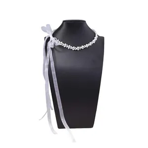 Detailed view of woven pearl choker with long translucent white ribbon bow