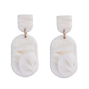 Detail view of white resin petal earrings with unique folded texture and gold link