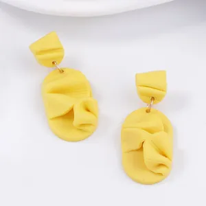 Detailed close-up of yellow polymer clay petal earrings with artistic folded textures