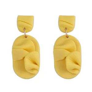 Macro detail of yellow petal-shaped polymer clay earrings with 3D wave textures