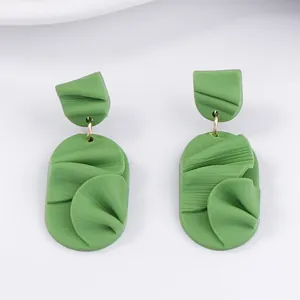 Macro detail of grass green handmade textured leaf-shaped geometric earrings