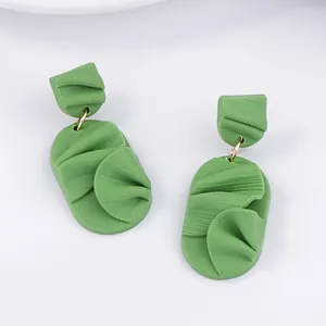 Macro detail of green petal-shaped earrings showing matte texture and gold metal rings