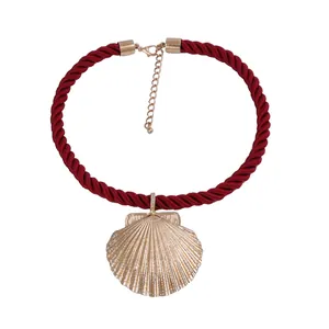 Deep red braided rope necklace featuring a textured golden seashell pendant detail