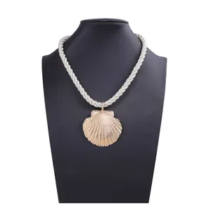 Close-up of golden seashell pendant with white braided rope chain on black neck display