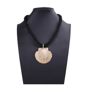 Macro detail of golden seashell pendant necklace with a black braided cord on a bust