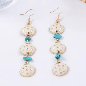 Détail de boucles d'oreilles géométriques en alliage avec pendentifs crème et perles