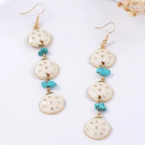 Détail de boucles d'oreilles bohèmes avec émail blanc et perles de turquoise