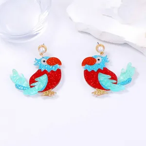 Gros plan de boucles d'oreilles perroquet en acrylique pailleté avec détails de perles