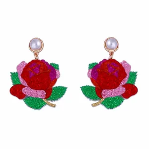 Gros plan de boucles d'oreilles rose à paillettes avec perles sur fond blanc pur
