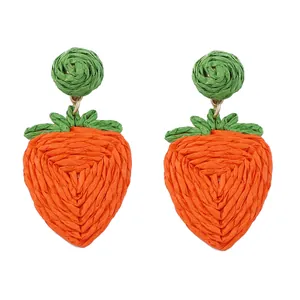 Handgemaakte geweven aardbei oorbellen van oranje raffia met groene bladeren