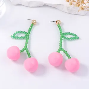 Detailed view of pink cherry fruit earrings with green beaded stems and golden studs