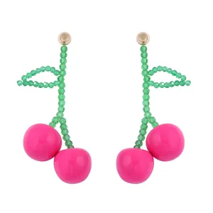 Detailed view of handmade beaded cherry drop earrings with glossy pink and green crystals