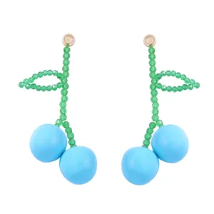 Close-up of handmade beaded cherry earrings with light blue fruit and gold metal studs
