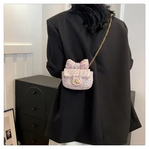 Detail der rosa Tweed-Mini-Umhängetasche mit Schleife und Kette am Modell