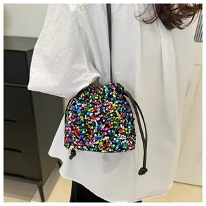Detailed view of colorful sequin drawstring bucket bag with black strap on white shirt