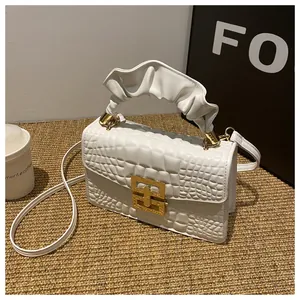 Detail of white crocodile embossed mini square bag with pleated handle and gold clasp