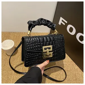 Close-up of black crocodile pattern PU handbag with golden buckle and ruched handle