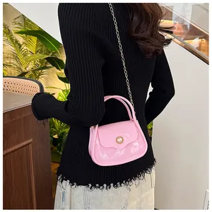 Pink jelly mini handbag with gold chain strap shown on model in a cozy interior setting