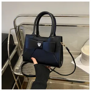 Detail einer stilvollen schwarzen Handtasche mit großer Schleife und Kristallherz im Regal
