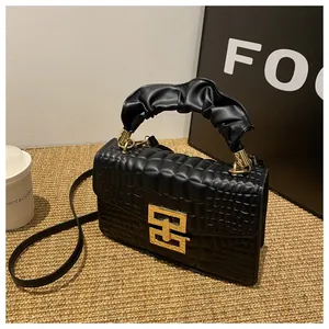 Detail of black crocodile texture bag featuring a unique pleated handle and gold clasp