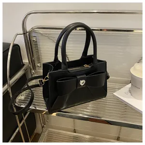 Nahaufnahme einer schwarzen Ledertasche mit großer Schleife und Herzkristall im Regal
