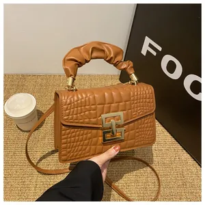 Detail of caramel crocodile embossed faux leather bag with gold buckle and ruched handle