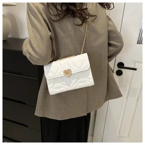 Back view of model wearing white heart-quilted chain bag over a brown suit jacket